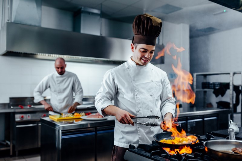 Cropped shot of a young male chef flambeing in a professional kitchen